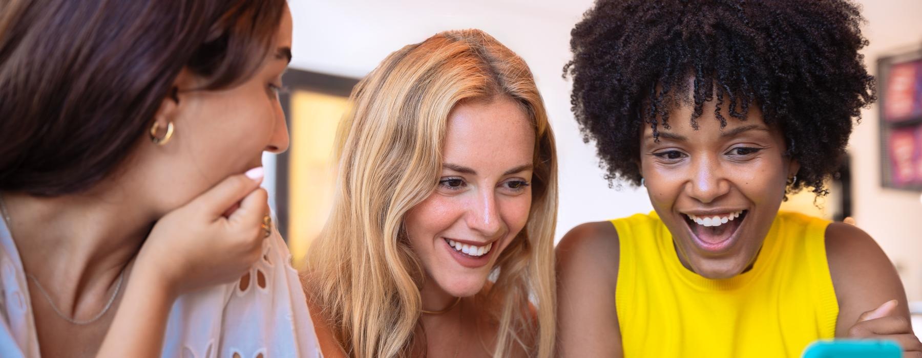 a group of women looking at a cell phone